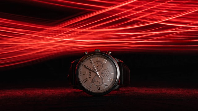 Relógio analógico em fundo escuro com luzes vermelhas